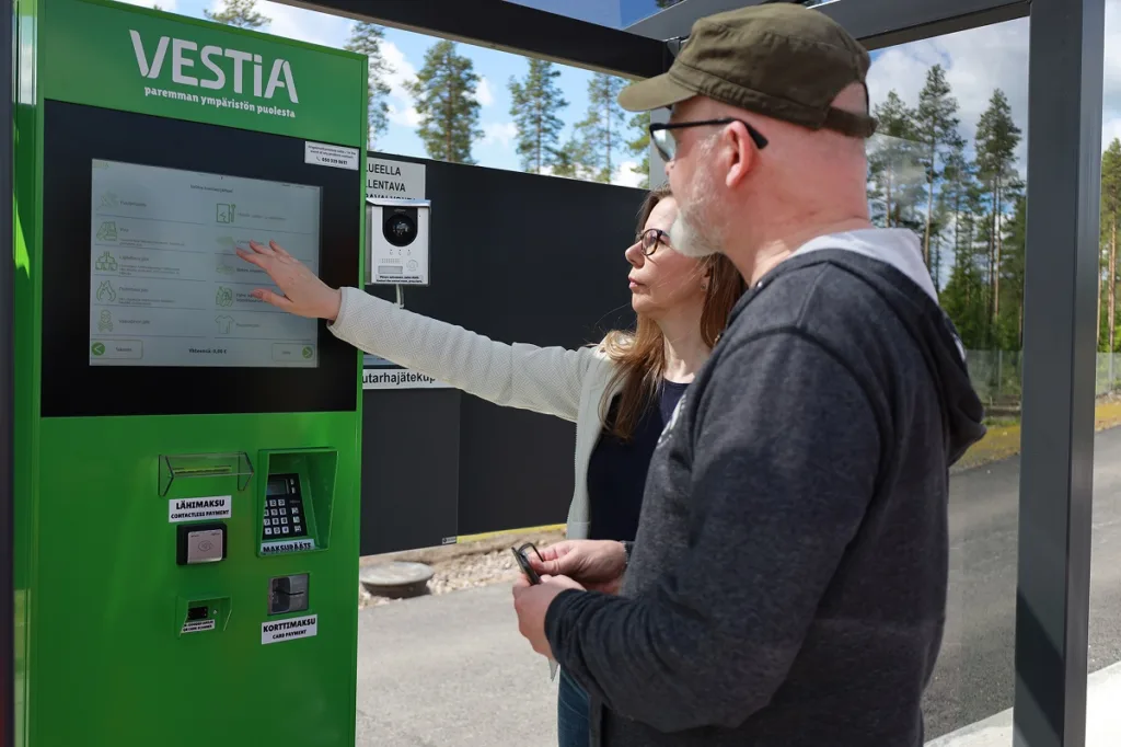 Kaksi henkilöä katsomassa Vestian lajittelupihan palveluautomaattia.